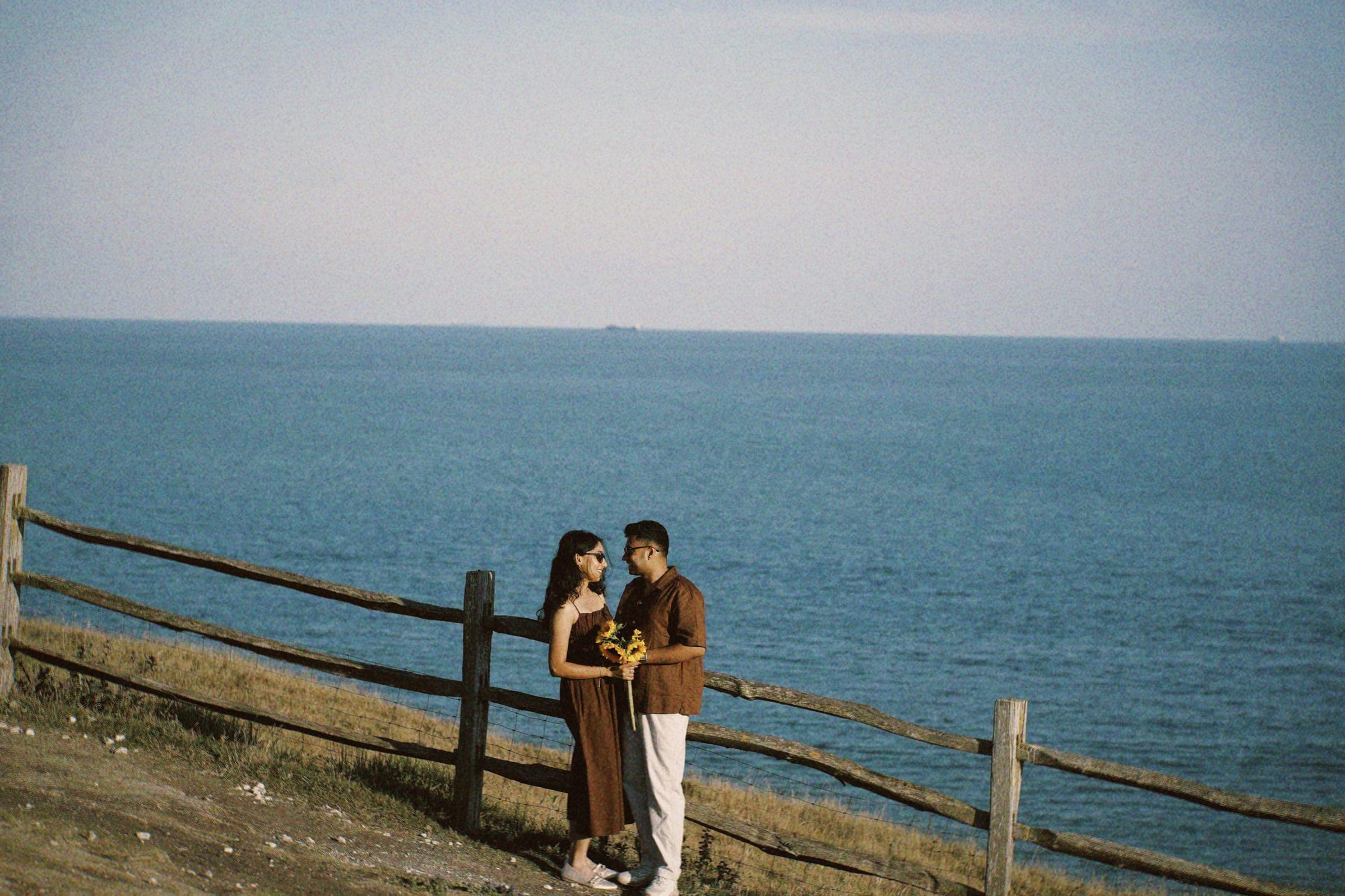 Arun and Anaina by the sea, holding sunflowers