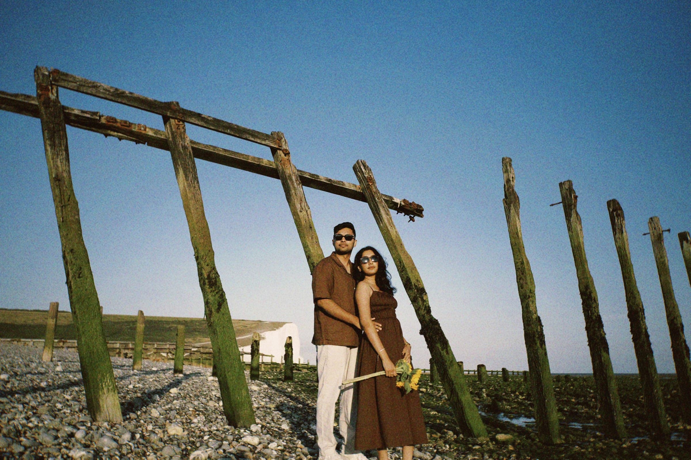 Arun and Anaina embracing beneath the old sea groynes