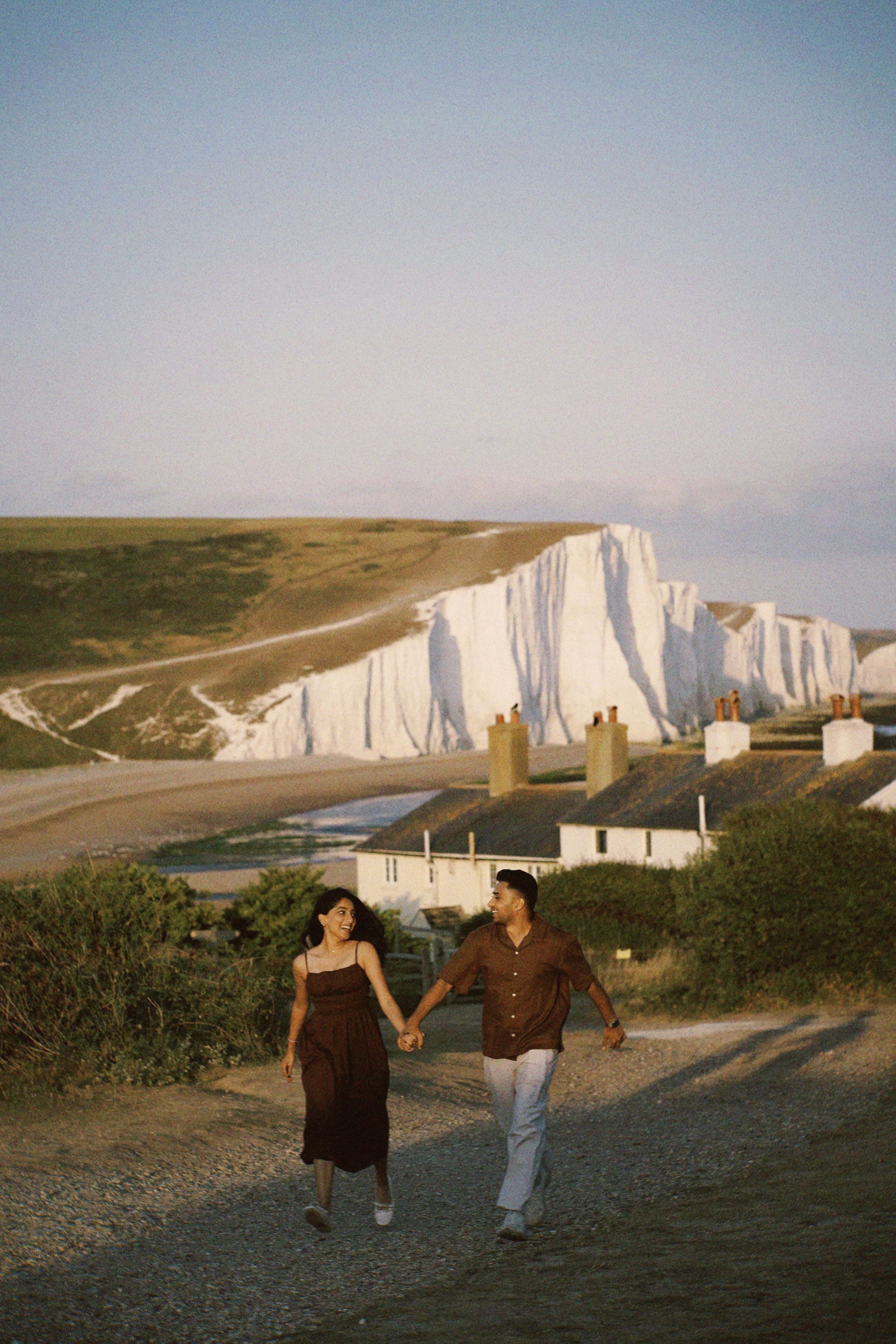 Arun and Anaina running hand in hand along the chalk cliffs at golden hour