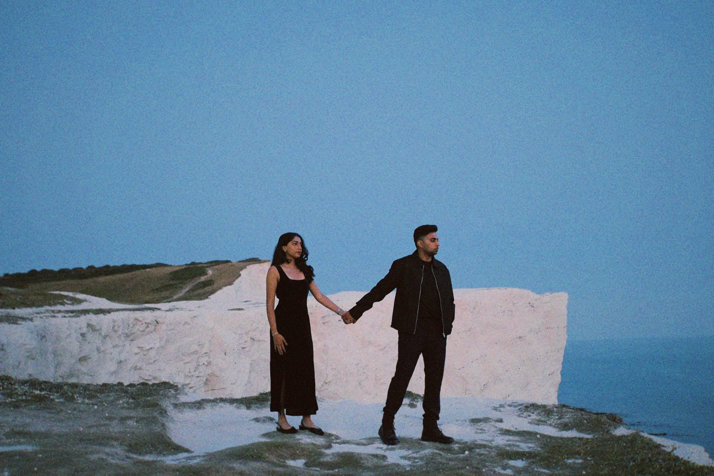 Arun and Anaina holding hands atop the chalk cliffs at dusk
