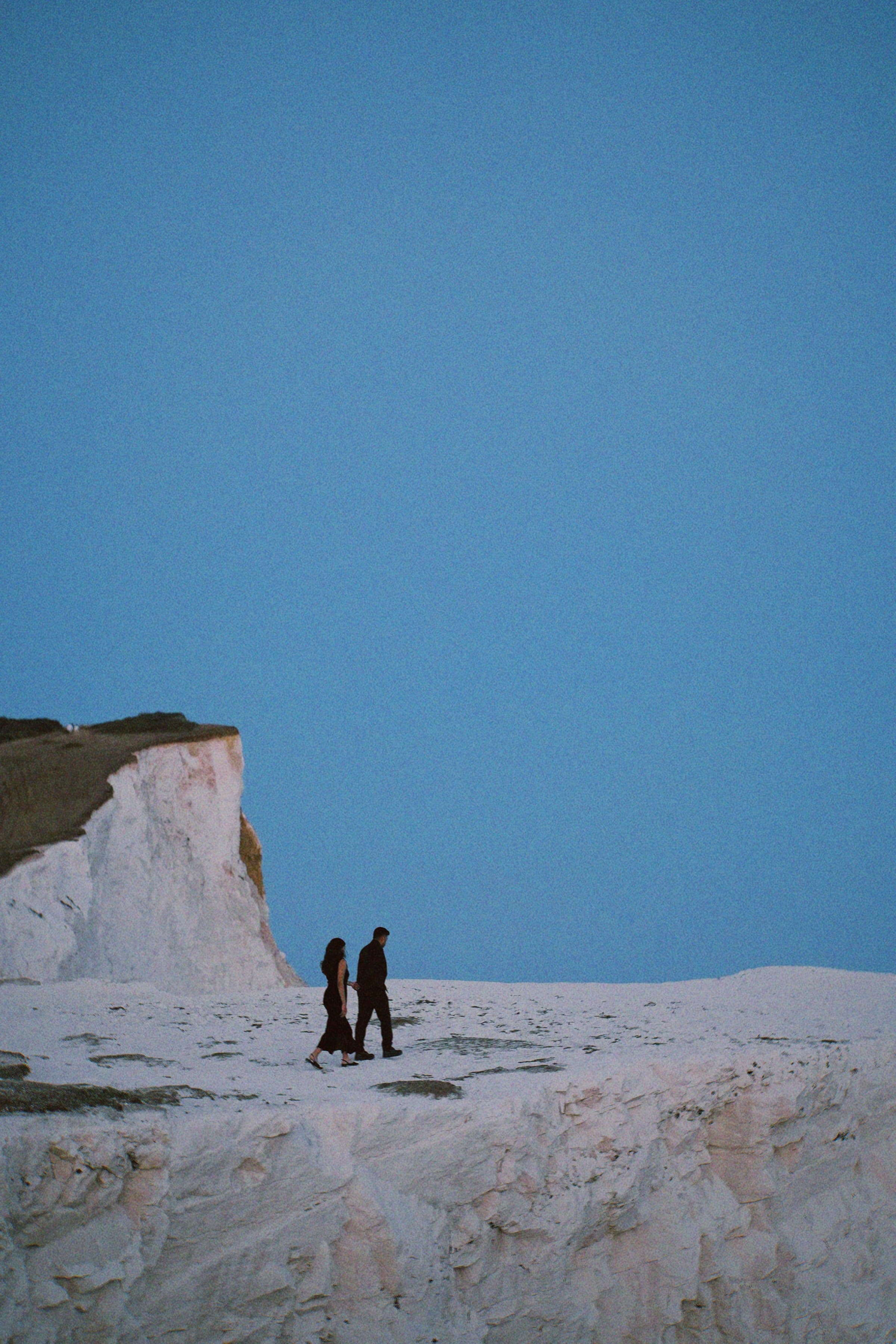 Arun and Anaina walking together along the cliff top at dusk